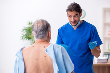 Old man visiting young male doctor dermatologist