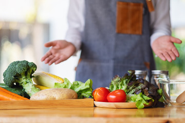 Closeup image of a female chef showing and preparing fresh mixed vegetables to cook in kitchen