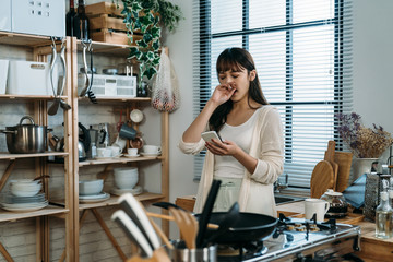 A tired Chinese woman just wake up yawning and reply the message to her friend in the kitchen,...