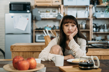 The young Japanese lady is worried about her interview of new technology job, and has breakfast in front of kitchen.