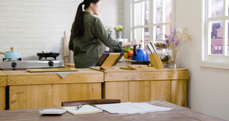 elegant asian chinese woman with kettle making tea at home kitchen wooden counter in background....