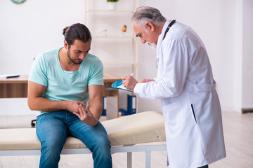 Obraz premium Injured young man visiting old doctor