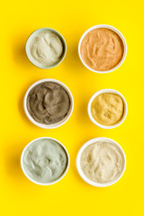 Blue, yellow, white. red, black cosmetic clay background on yellow table top-down