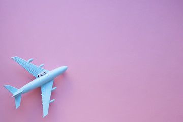 Fly word and airplane model on a pink background. Travel concept