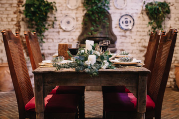 A table setting  designed for an intimate boho style event with rustic touches and red velvet chair