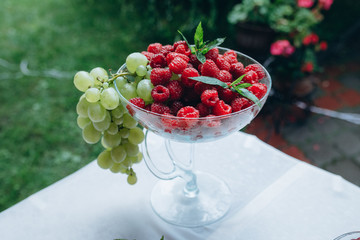 Fototapeta na wymiar fruit salad of raspberry, mint, grapes in a glass sundae dish, close up.
