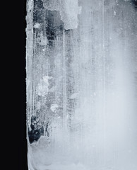 Blue toned transparent ice block, on white surface, isolated on black background.