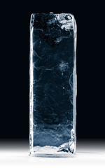 Blue toned transparent ice block, on white surface, isolated on black background.