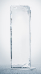 Blue toned transparent ice block, on white surface, isolated on white background. Clipping path included.