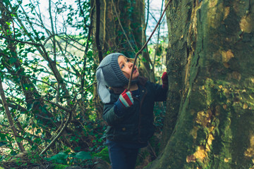 Little preschooler playing with sticks in the woods