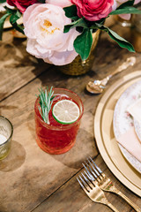 A signature alcoholic cocktail garnished with lime and rosemary on a rustic surface