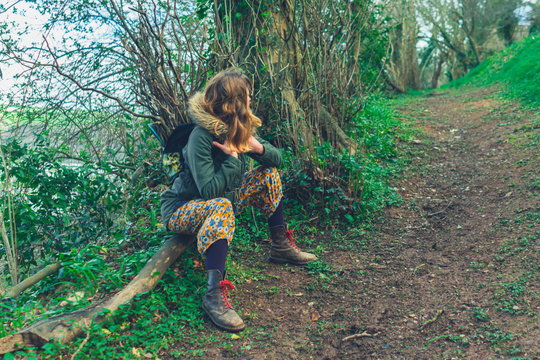 Young woman relaxing after collecting sticks in the woods