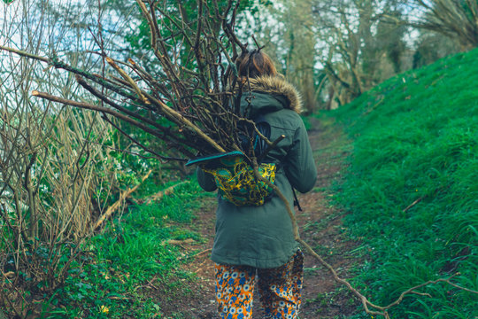Young woman with a backpack full of sticks walking in the woods