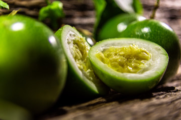 Passion fruit (Passiflora edulis) fruits and pulp on wooden background and green leaves