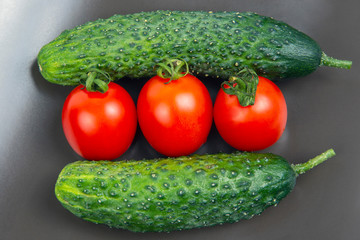 Fresh cucumbers and tomatoes on a gray background. vitamins and light breakfast