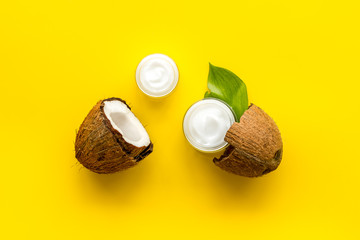 Face care. Coconut cream in glass jar on yellow background top-down