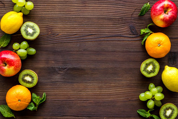 Fresh fruits background with citruses, apple, kiwi and grape on wooden table top-down frame copy space