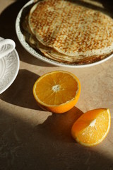 Pancakes and oranges on the table in the kitchen on a sunny day