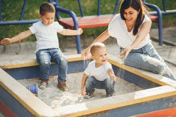 Family in a park. Mother with sons playing with a sand. People on a playground.