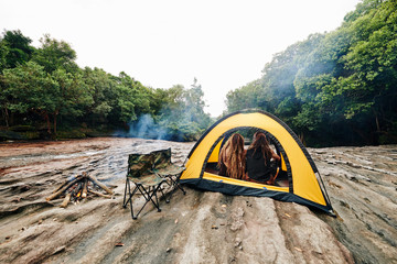 Couple sitting by fireplace and enjoying view from the tent, view fromt the back