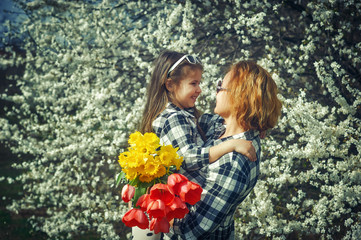 mother and daughter with flowers at a flowering tree .Family value .