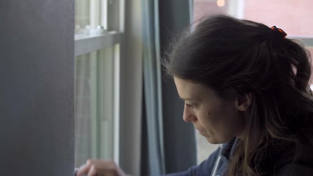 Attractive woman cleaning windows at her home inside during the day and doing some spring cleaning