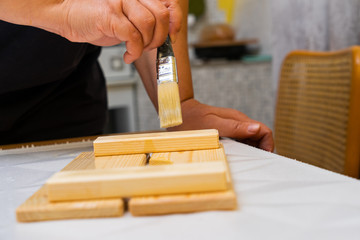 Girl varnishes a wooden detail.