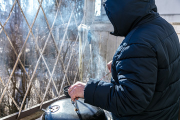 A man is grilling sausages in his yard.   Finland March 2020