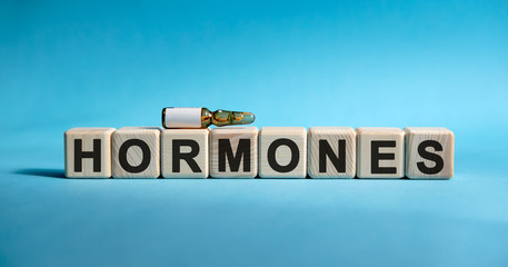 HORMONES - text on cubes. Drug in ambula to reduce disease symptoms on a blue background
