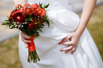 Close-up of the hands of a bride who is holding a wedding bouquet of flowers. Wedding day.