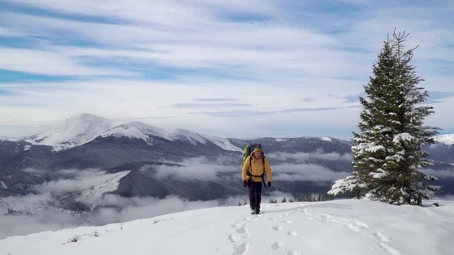 A man with a backpack travels in the mountains in winter. Carpathian mountain range. The concept of travel and active lifestyle. 4K