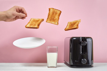 Toasts flew out of toaster. Near glass of milk. Levitation food. Delicious morning breakfast on...