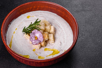 Delicious beautiful mushroom soup in a brown plate with a wooden spoon