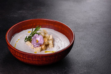 Delicious beautiful mushroom soup in a brown plate with a wooden spoon