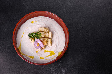 Delicious beautiful mushroom soup in a brown plate with a wooden spoon