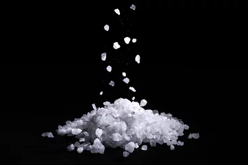 Fotobehang Sea salt crystals fall on a pile of salt, black background © wertinio