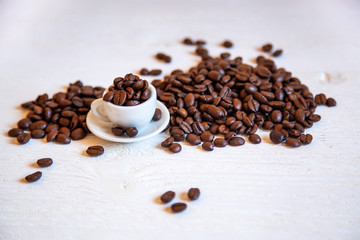Small cup with coffee beans on the white table