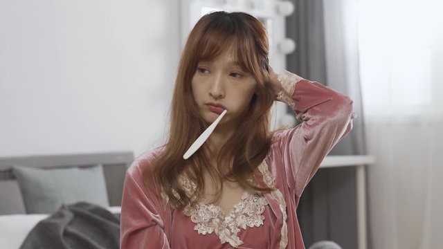 daytime sleepy korean girl holding toothbrush is dozing off while cleaning teeth. asian woman found herself drowsing feels embarrassed, scratching head and keeps brushing teeth.