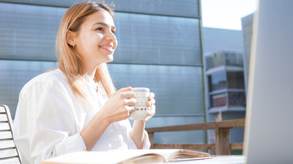 Happy student female studying and working from home. Attractive business woman professional enjoying cup of coffee on a sunny day. 