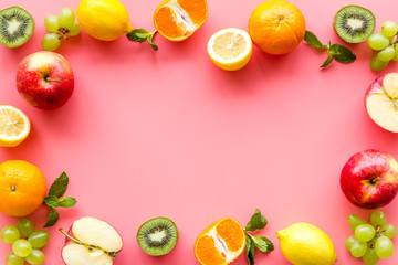 Oranges, lemon, apple, kiwi and grape - healthy food concept with fruits - on pink background top-down frame copy space