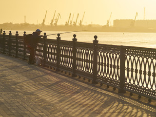 Russia Astrakhan - 09.30.2015: Silhouette of fisherman over sunset in the city