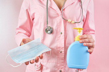 Doctor holds textile medical masks and soap in his hand on a pink background. Protective accessory against viruses