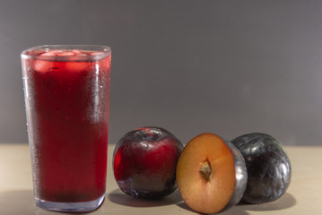 Plum juice and fruits (Prunus Alleghaniensis) on dark background