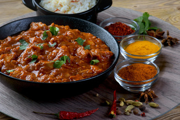 chicken curry with spices and rice on a dark background