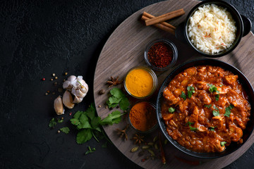 chicken curry with spices and rice on a dark background