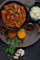 chicken curry with spices and rice on a dark background