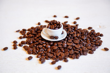 Small cup with coffee beans on the white table