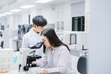 Two  medical  scientist working in Medical laboratory , young female scientist looking at microscope. select focus in young  female scientist