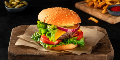 Burger panorama on a dark background with pickles and French fries