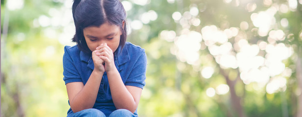 Pray concept.Asian child praying, hope for peace and free from disease, Hand in hand together by kid, believes and faith in christian religion at church-panoramic banner for web header.